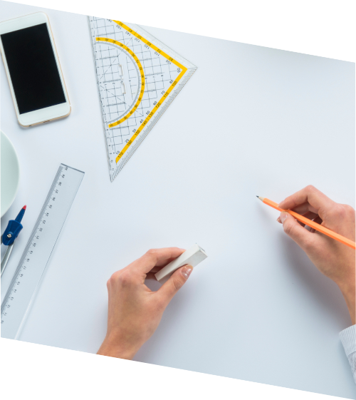 Construction Management: A birds-eye view of hands over a blank piece of paper. In one hand is a pencil, in the other is an eraser. Sitting on the table is a protractor, ruler, and iPhone. Construction Management: A birds-eye view of hands over a blank piece of paper. In one hand is a pencil, in the other is an eraser. Sitting on the table is a protractor, ruler, and iPhone.
